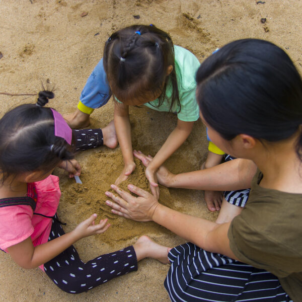 Mom playing in sand with kids