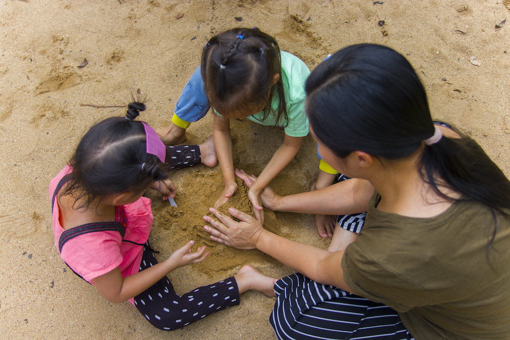 Mom playing in sand with kids